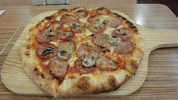 a pepperoni and mushroom pizza served on a wooden peel